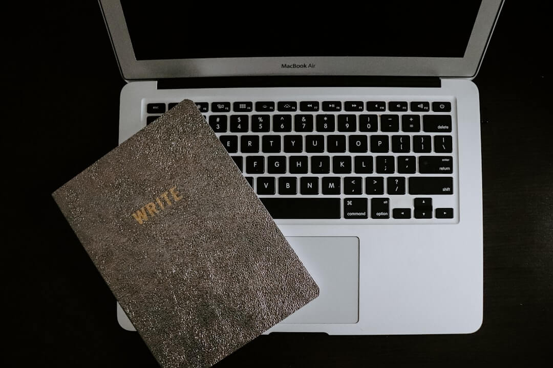 Laptop showing a structured manuscript beside printed pages and a notebook